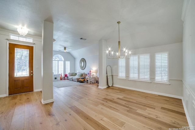 foyer entrance with visible vents, light wood-style floors, vaulted ceiling, baseboards, and ceiling fan with notable chandelier