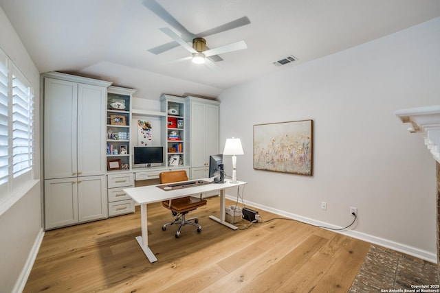 home office with light wood-style flooring, visible vents, vaulted ceiling, and baseboards