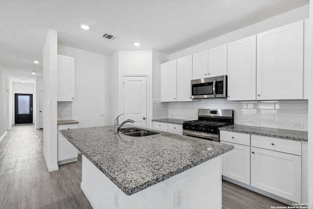 kitchen with stainless steel appliances, stone countertops, visible vents, and a sink