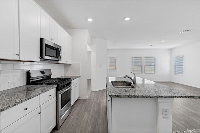 kitchen featuring appliances with stainless steel finishes, stone countertops, a sink, and light wood finished floors