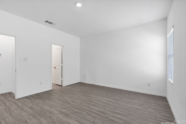 empty room with a healthy amount of sunlight, visible vents, baseboards, and wood finished floors