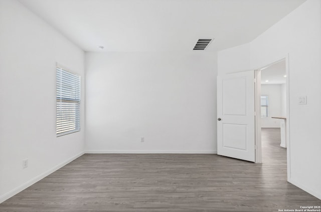 unfurnished room with a healthy amount of sunlight, baseboards, and wood finished floors