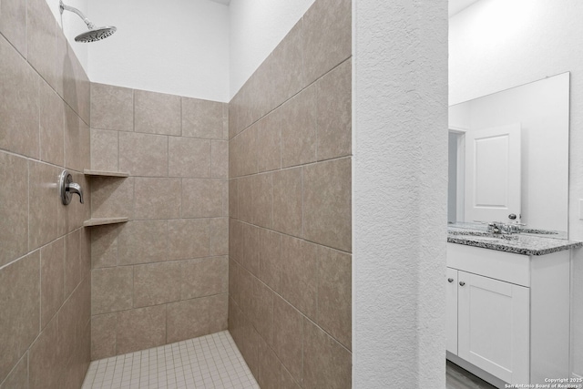 bathroom with tiled shower and vanity