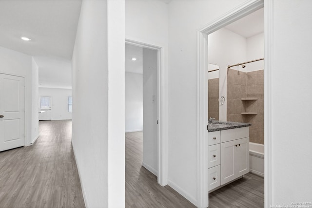 corridor featuring recessed lighting, light wood-style flooring, and baseboards