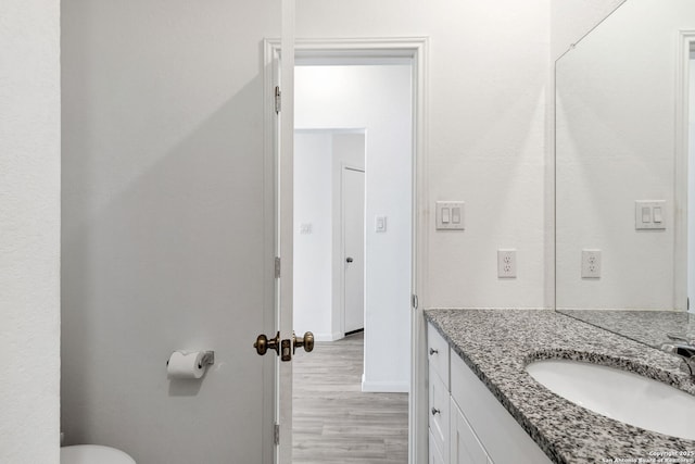 bathroom featuring toilet, vanity, baseboards, and wood finished floors