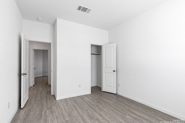 unfurnished bedroom featuring light wood-style floors, a closet, visible vents, and baseboards