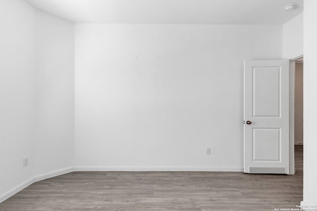 spare room featuring baseboards and wood finished floors