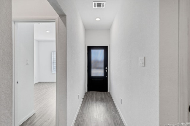 hall featuring wood finished floors, visible vents, and baseboards