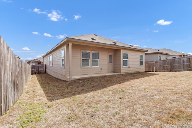 rear view of property featuring a fenced backyard and a yard