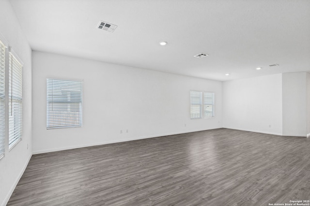 unfurnished room with dark wood-style flooring, recessed lighting, visible vents, and baseboards