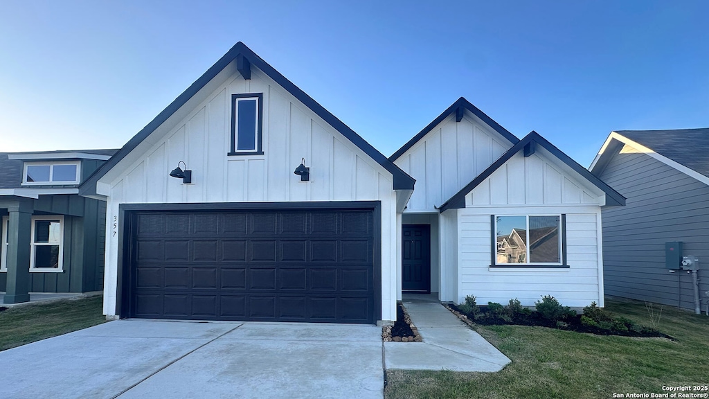 modern inspired farmhouse featuring an attached garage, driveway, board and batten siding, and a front yard