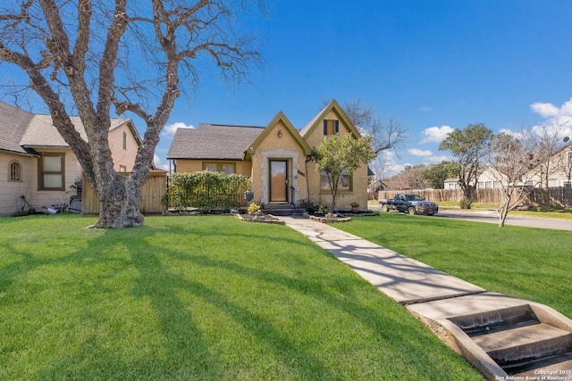 view of front facade with roof with shingles, fence, and a front yard