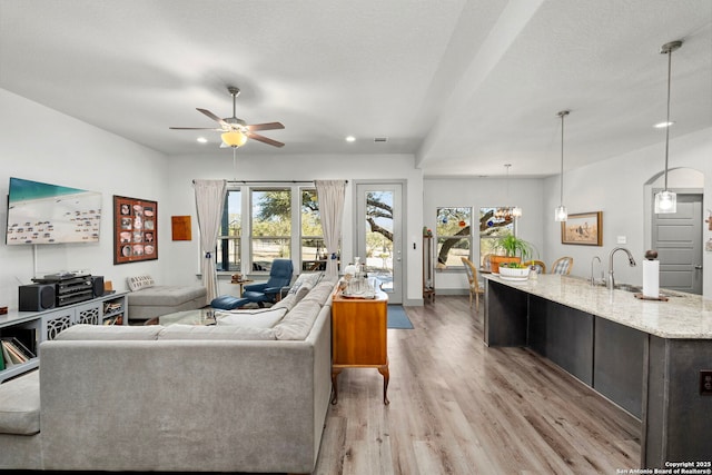 living area featuring ceiling fan, light wood-style flooring, and a textured ceiling