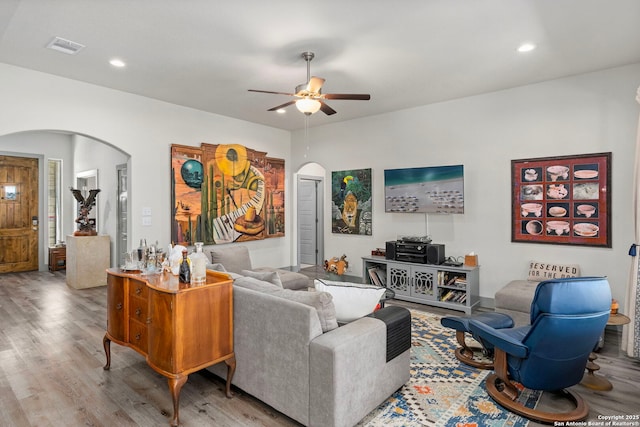 living area featuring arched walkways, ceiling fan, recessed lighting, and wood finished floors