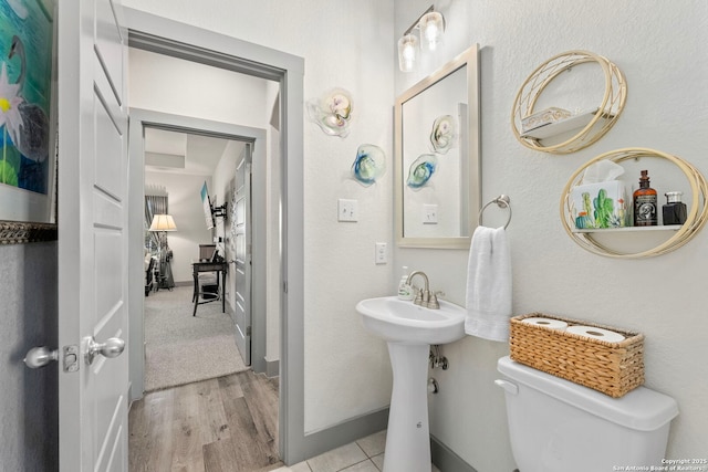 bathroom with baseboards, toilet, and wood finished floors