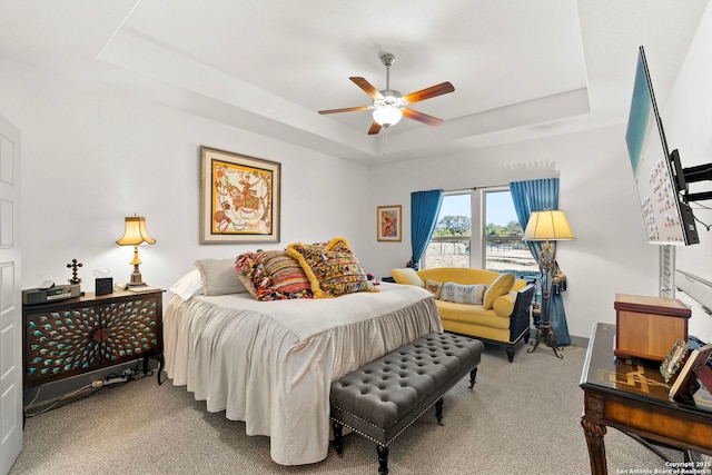 bedroom with carpet, a raised ceiling, and a ceiling fan