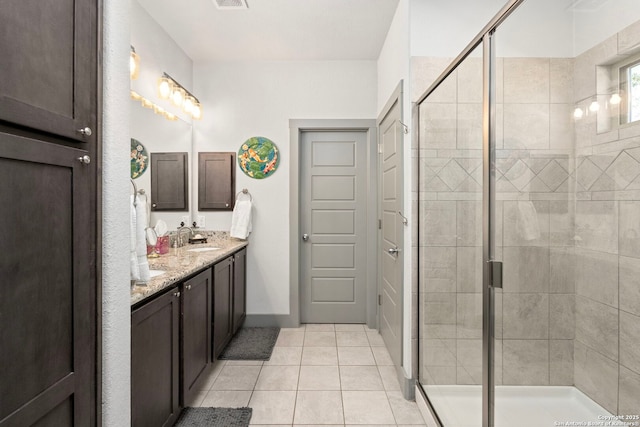 bathroom with double vanity, a sink, a shower stall, and tile patterned floors