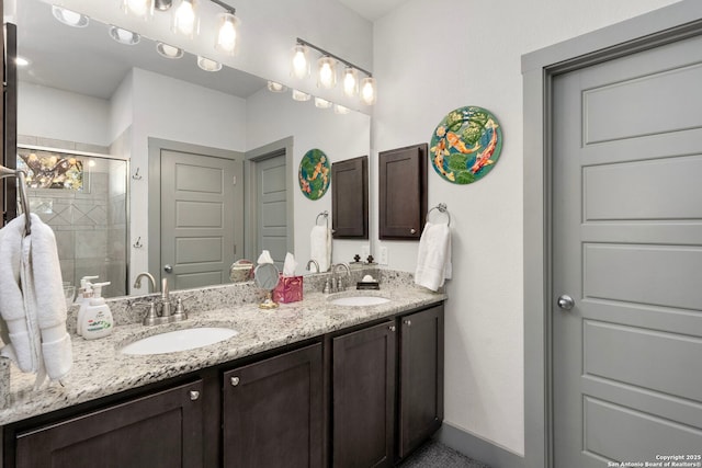 full bathroom featuring baseboards, double vanity, a sink, and a shower stall