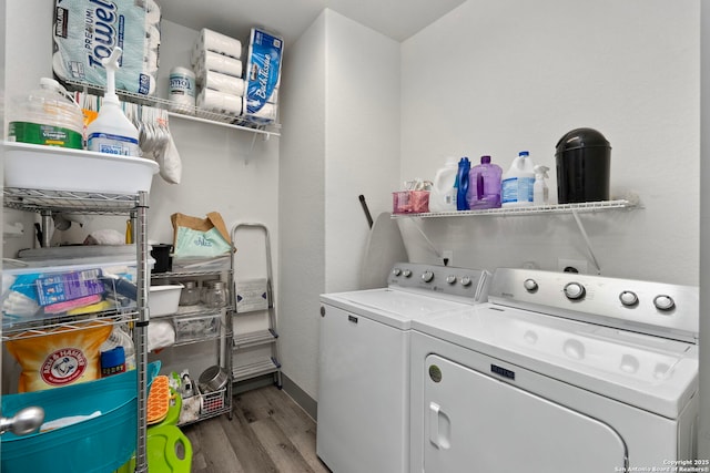 clothes washing area with laundry area, washing machine and clothes dryer, and wood finished floors