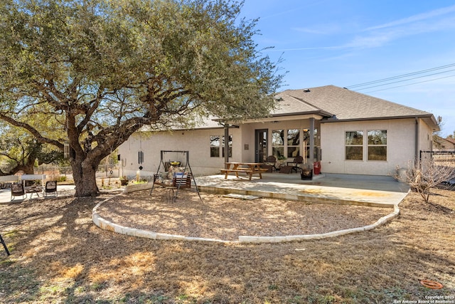 rear view of property featuring roof with shingles, a patio area, fence, and stucco siding