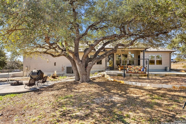 rear view of property featuring an outdoor fire pit, fence, central AC, and a patio