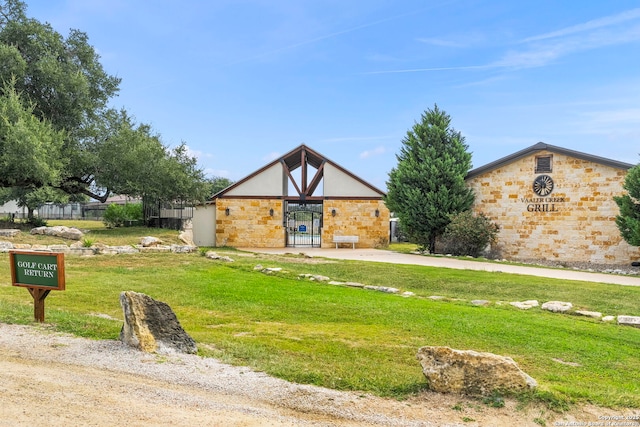 view of front of home featuring stone siding, fence, and a front yard