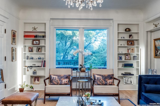 sitting room featuring a chandelier, wood finished floors, and built in features