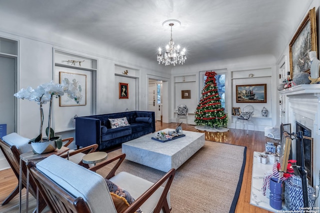 living area with a notable chandelier, wood finished floors, a high end fireplace, and built in features