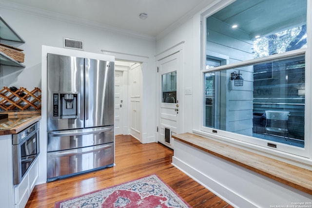 kitchen featuring visible vents, appliances with stainless steel finishes, wood finished floors, crown molding, and wooden counters