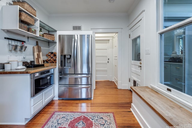 kitchen featuring light wood finished floors, visible vents, stainless steel appliances, and crown molding