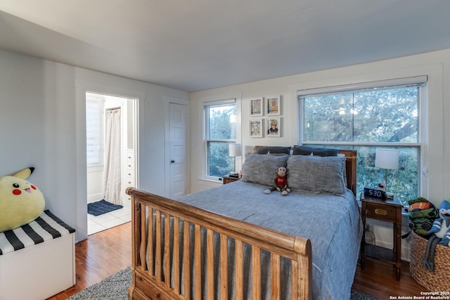 bedroom with connected bathroom and wood finished floors