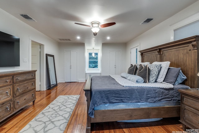 bedroom featuring light wood-style floors, visible vents, and a ceiling fan