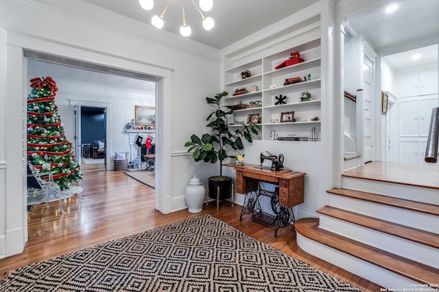 corridor with a chandelier, stairway, and wood finished floors