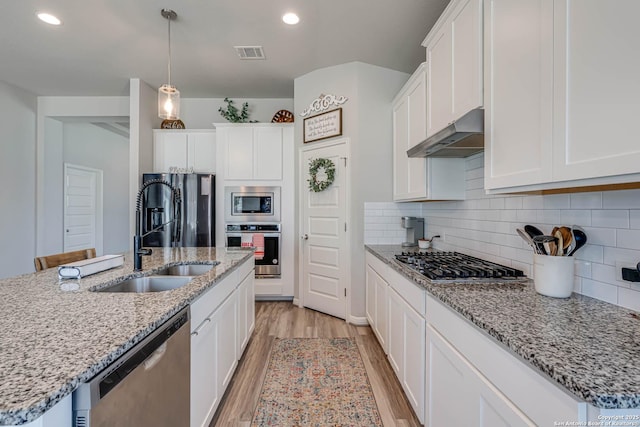 kitchen with visible vents, appliances with stainless steel finishes, light wood-type flooring, under cabinet range hood, and a sink