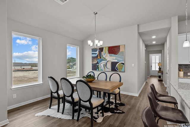 dining area featuring dark wood-type flooring, plenty of natural light, baseboards, and an inviting chandelier