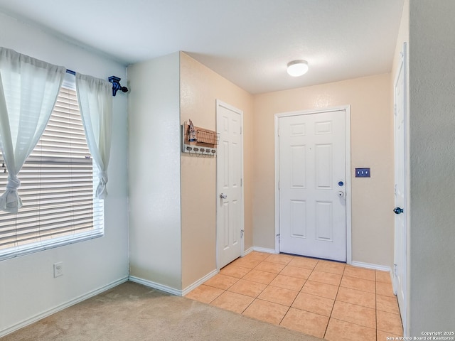 entrance foyer featuring a healthy amount of sunlight, light carpet, baseboards, and light tile patterned flooring