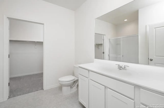 bathroom with baseboards, vanity, toilet, and a walk in closet