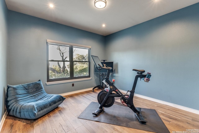 exercise area featuring recessed lighting, wood finished floors, and baseboards