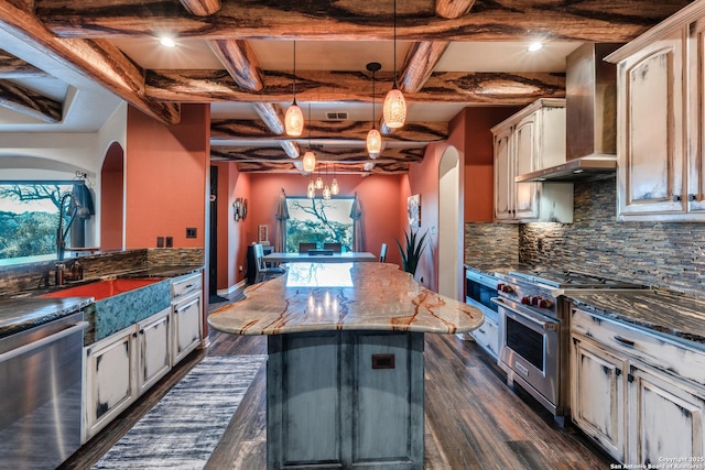 kitchen featuring arched walkways, appliances with stainless steel finishes, dark wood-style floors, wall chimney exhaust hood, and tasteful backsplash