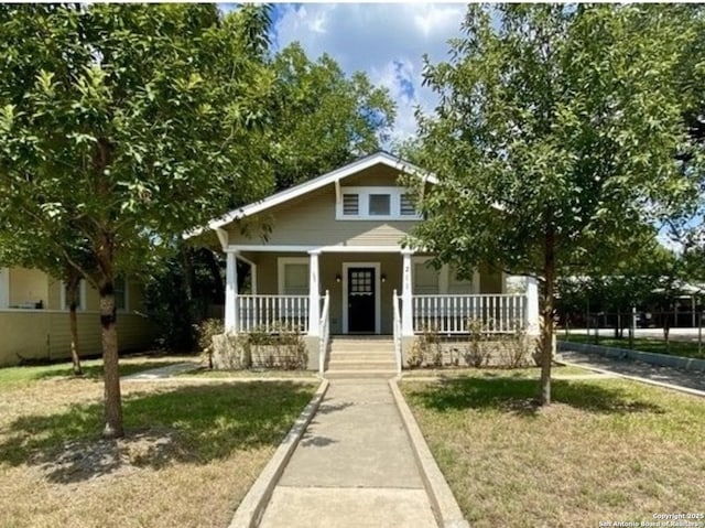 bungalow-style home featuring covered porch and a front lawn