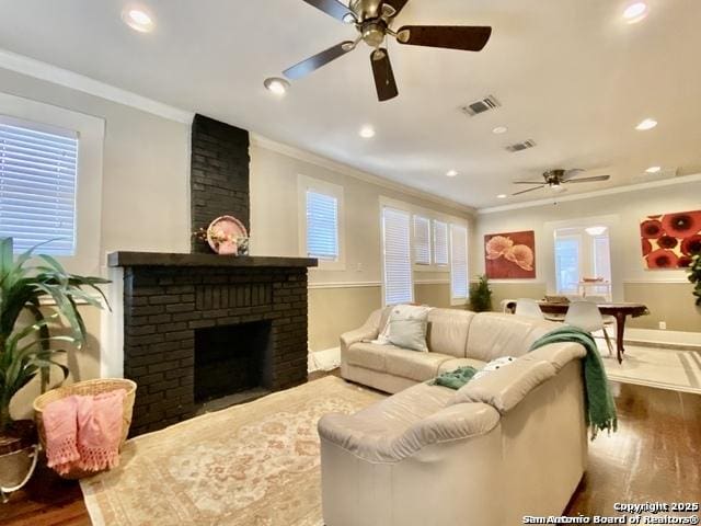 living area featuring a fireplace, wood finished floors, and crown molding