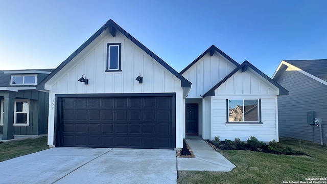 modern inspired farmhouse with concrete driveway, a front lawn, board and batten siding, and an attached garage