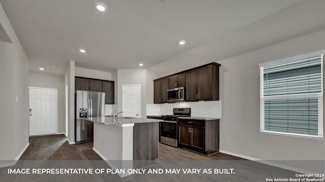 kitchen with dark brown cabinetry, a center island with sink, light stone counters, dark wood-style flooring, and stainless steel appliances