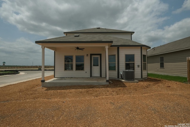 rear view of house with central AC, a ceiling fan, a patio area, and roof with shingles