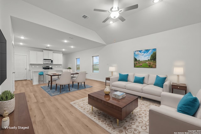 living area featuring lofted ceiling, light wood finished floors, ceiling fan, and recessed lighting