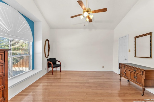 sitting room featuring light wood-type flooring, baseboards, vaulted ceiling, and a ceiling fan