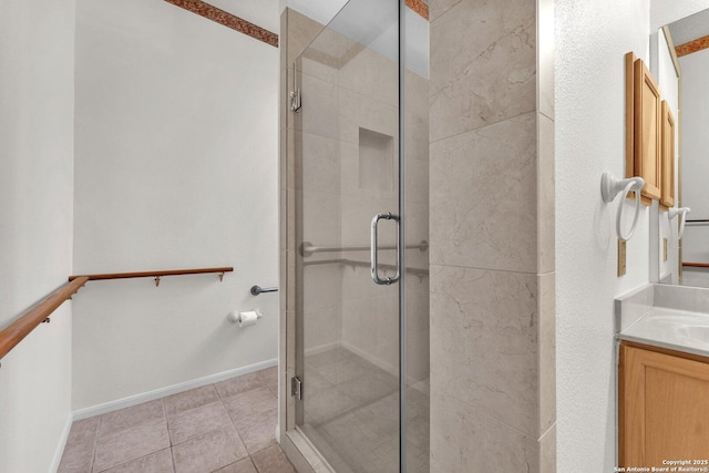 bathroom featuring tile patterned flooring, baseboards, a shower stall, and vanity