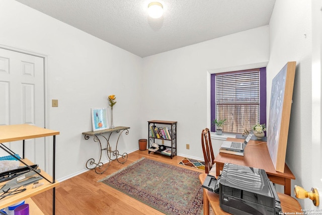 office with a textured ceiling, baseboards, and wood finished floors