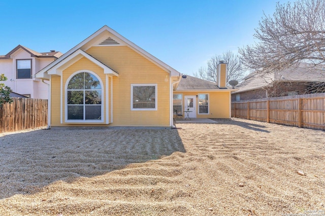 rear view of house featuring fence, a chimney, and a patio