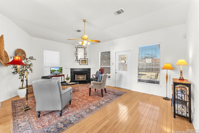 living area with hardwood / wood-style flooring, visible vents, a wealth of natural light, and a tiled fireplace